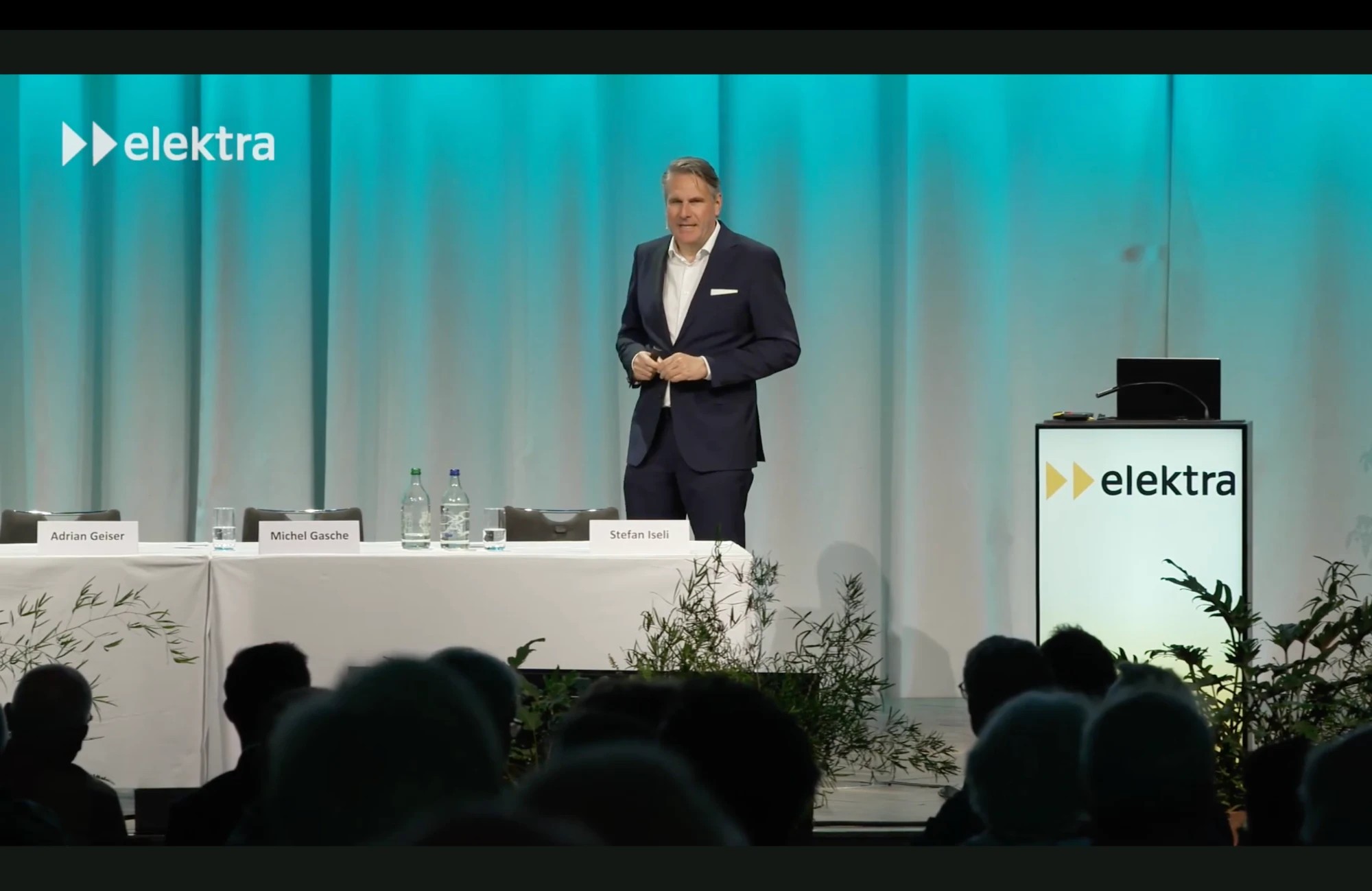 Prof. Dr. Christian Stummeyer auf der Bühne im Kursaal Bern, im Vordergrund der Vorstandstisch mit den Namensschildern