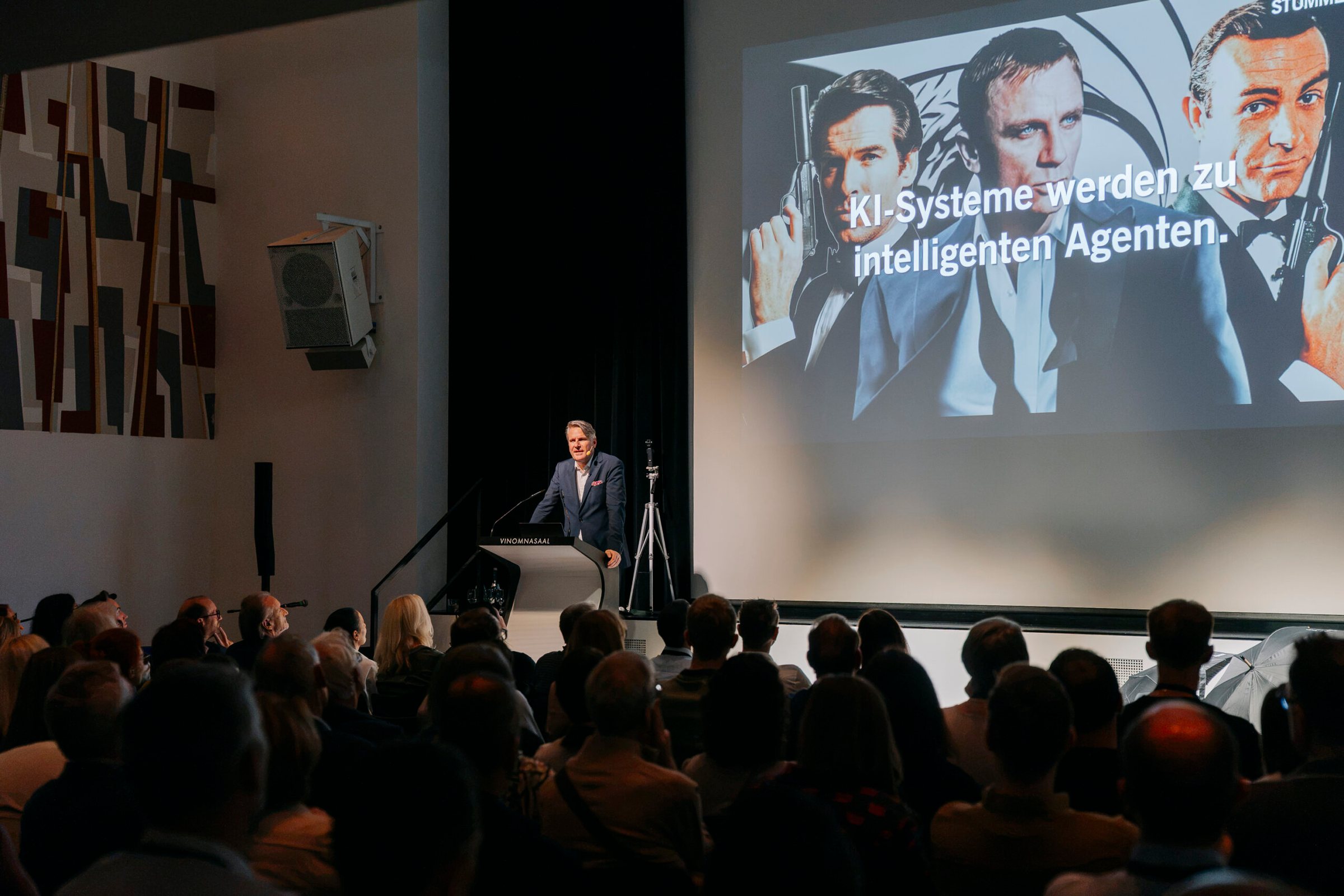 Prof. Dr. Christian Stummeyer am Rednerpult im Vinomnasaal vor der Folie „KI-Systeme werden zu intelligenten Agenten“