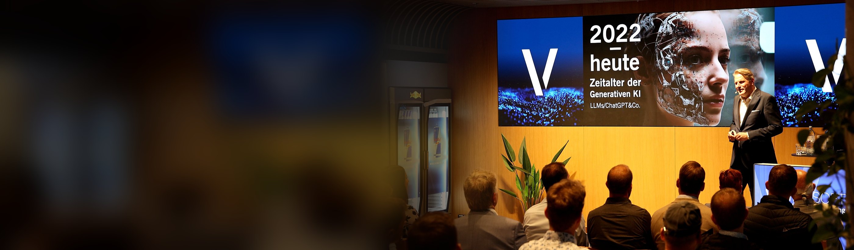 Prof. Dr. Christian Stummeyer auf der Bühne des VENDOeVent 26 im SAP Garden München, auf der Leinwand die Folie „2022 – heute: Zeitalter der Generativen KI“
